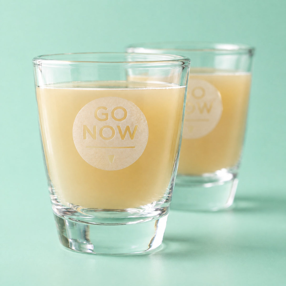 Close-up van een Go Now shotglas gevuld met gembersap