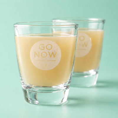 Close-up van een Go Now shotglas gevuld met gembersap