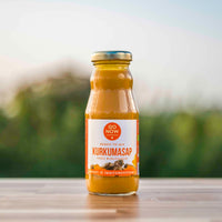 Flesje Go Now Pure Kurkumasap 200ml buiten op een houten tafel