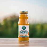 Flesje Go Now Gember Shot 200ml met mandarijn en gember, buiten op een houten tafel