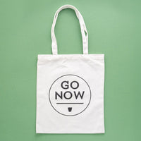 Witte katoenen Go Now-draagtas met logo op een groene achtergrond